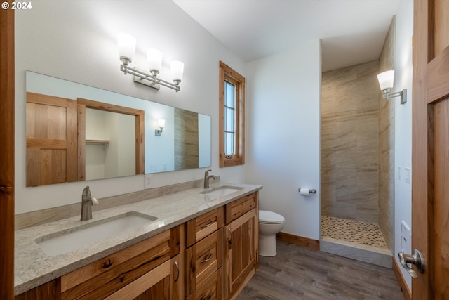 bathroom with tiled shower, wood-type flooring, vanity, and toilet