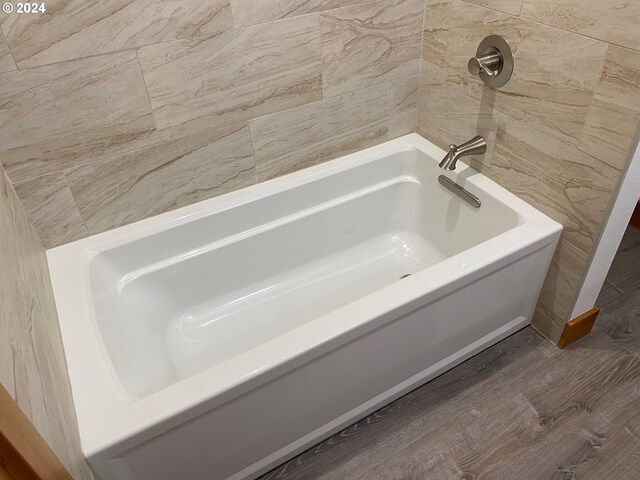 bathroom with hardwood / wood-style flooring and a bath