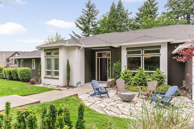 back of property with an outdoor fire pit, a patio area, and a lawn