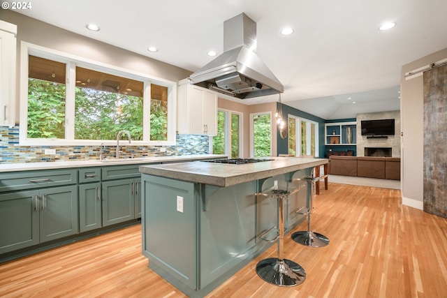 kitchen with decorative backsplash, island range hood, sink, a kitchen island, and hanging light fixtures