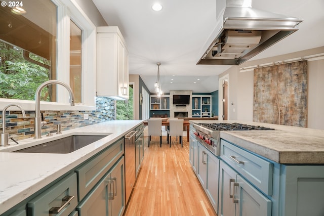 kitchen with light stone countertops, sink, light hardwood / wood-style floors, decorative light fixtures, and white cabinets