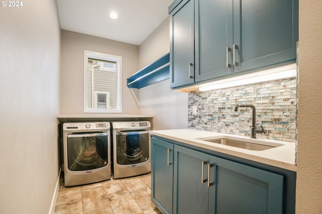 clothes washing area featuring cabinets, sink, light tile patterned flooring, and washing machine and clothes dryer