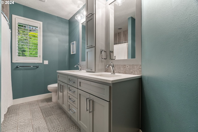 bathroom with vanity, a textured ceiling, toilet, and tile patterned flooring