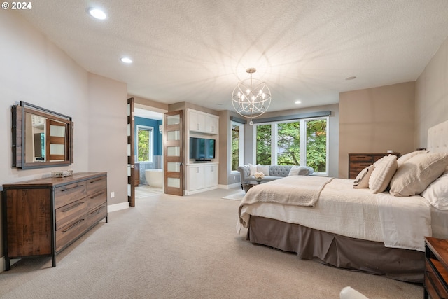 carpeted bedroom with a notable chandelier, a textured ceiling, and ensuite bath