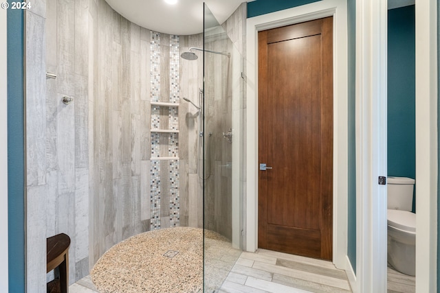 bathroom featuring tiled shower, hardwood / wood-style flooring, and toilet