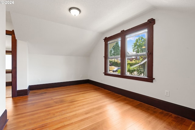 bonus room featuring hardwood / wood-style floors, vaulted ceiling, and a textured ceiling