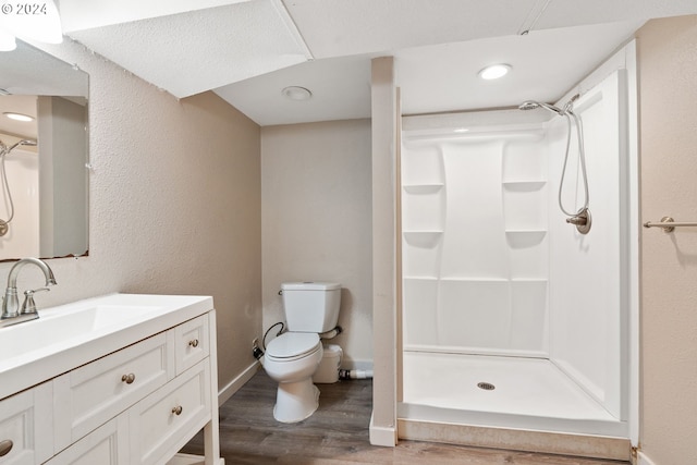 bathroom with toilet, hardwood / wood-style floors, vanity, and walk in shower