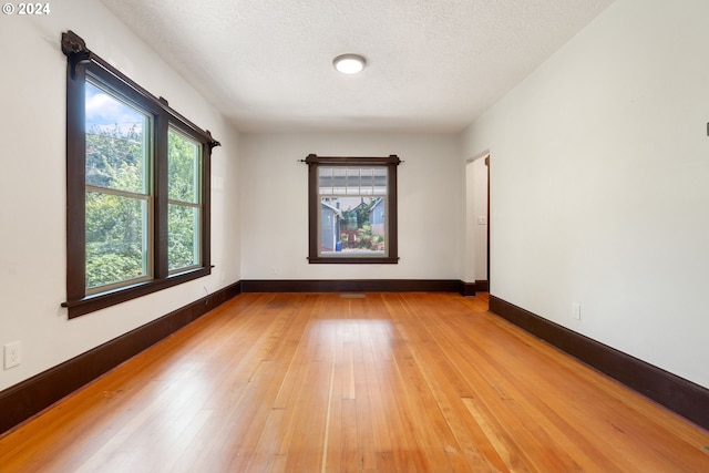 spare room with a textured ceiling and light hardwood / wood-style floors