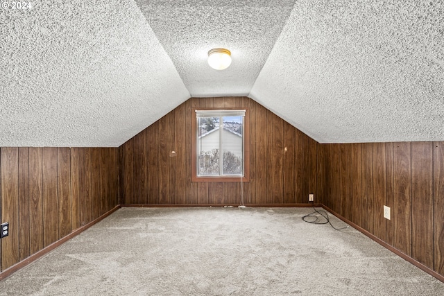 bonus room featuring a textured ceiling, wood walls, and light carpet