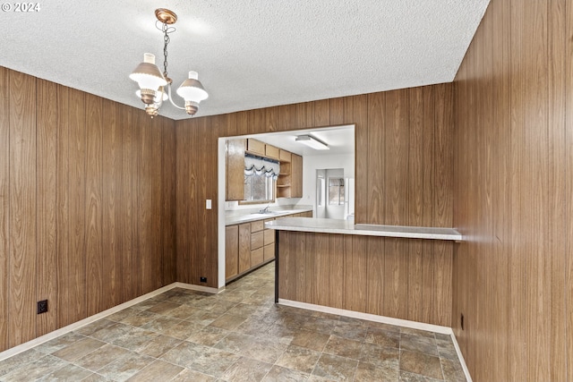 kitchen with kitchen peninsula, wood walls, pendant lighting, and a chandelier