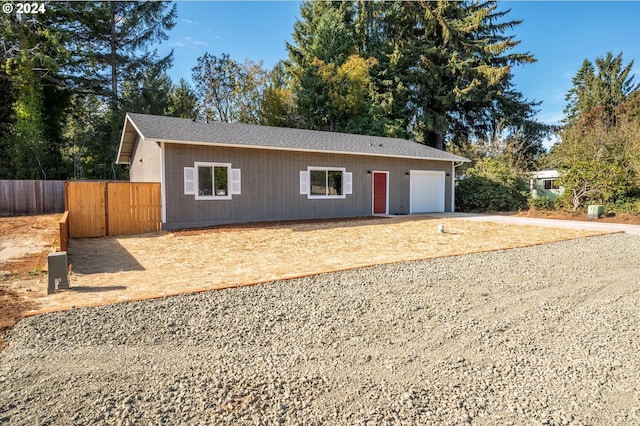single story home with concrete driveway, fence, and an attached garage