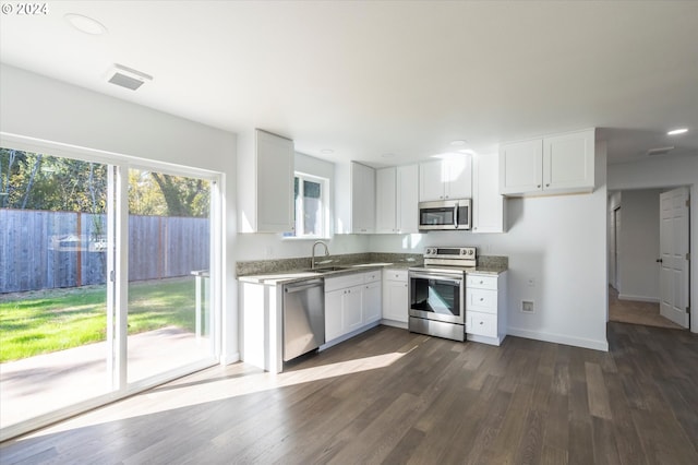 kitchen with sink, light stone counters, dark hardwood / wood-style floors, white cabinets, and appliances with stainless steel finishes