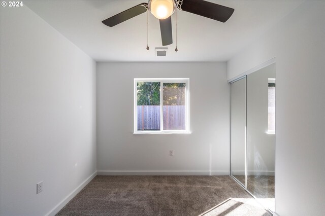 unfurnished bedroom featuring a closet, ceiling fan, and dark colored carpet