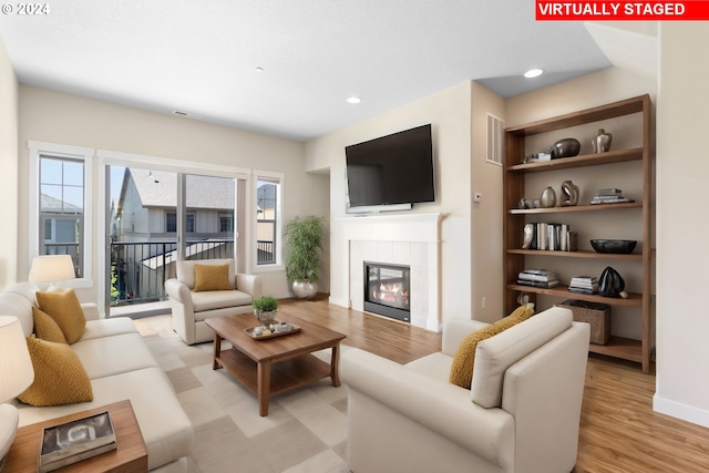 living room with a tile fireplace and light hardwood / wood-style flooring