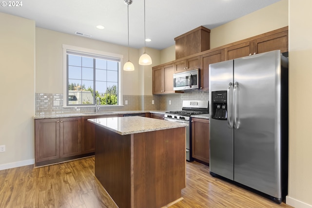 kitchen with light hardwood / wood-style flooring, a center island, decorative light fixtures, and stainless steel appliances