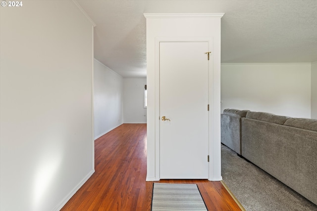 hallway featuring dark hardwood / wood-style floors, crown molding, and a textured ceiling