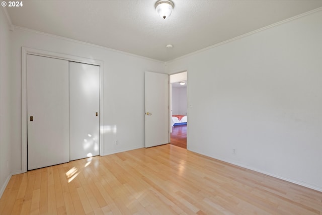 unfurnished bedroom with crown molding, a closet, a textured ceiling, and light wood-type flooring