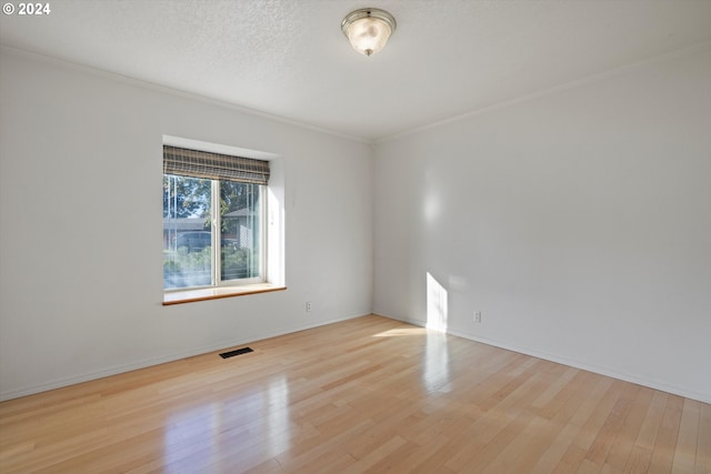 unfurnished room with a textured ceiling, crown molding, and light hardwood / wood-style flooring