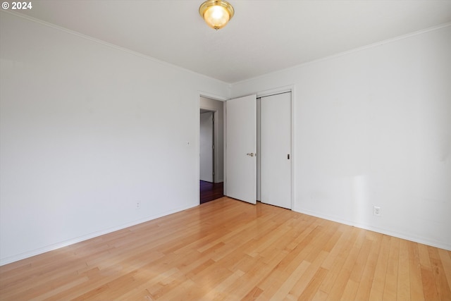 unfurnished bedroom featuring wood-type flooring, a closet, and ornamental molding