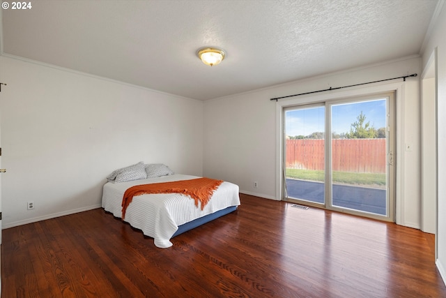 bedroom with access to exterior, a textured ceiling, dark hardwood / wood-style floors, and ornamental molding