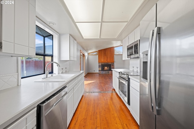 kitchen with white cabinetry, sink, stainless steel appliances, light hardwood / wood-style flooring, and decorative light fixtures