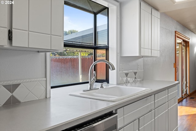 kitchen with dishwasher, sink, white cabinets, and hardwood / wood-style flooring