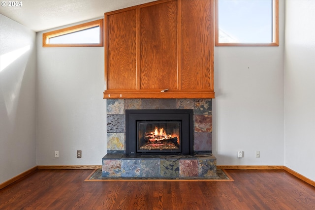 interior details featuring a tiled fireplace and wood-type flooring