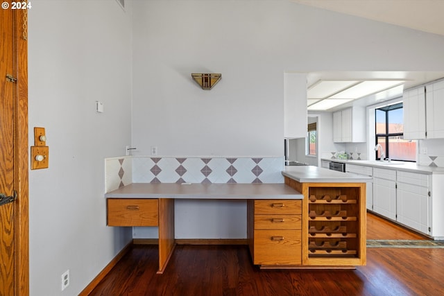 kitchen with white cabinetry, sink, dark wood-type flooring, kitchen peninsula, and vaulted ceiling