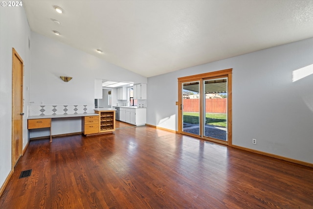 unfurnished living room featuring built in desk, dark hardwood / wood-style floors, and vaulted ceiling