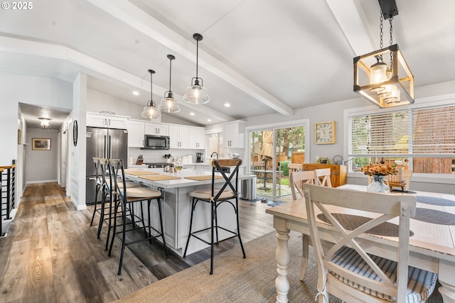 kitchen with high end refrigerator, lofted ceiling with beams, white cabinets, pendant lighting, and backsplash