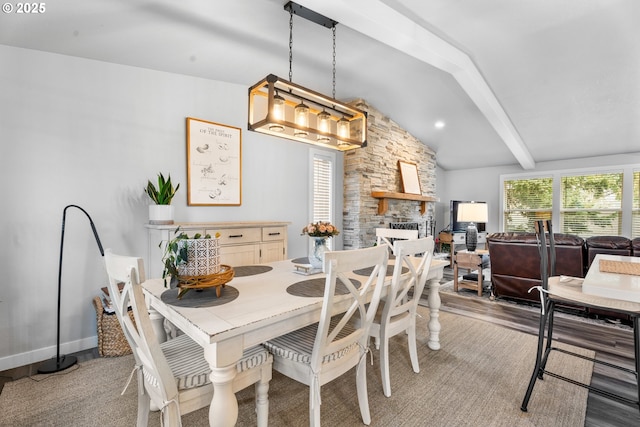 dining room featuring a fireplace, lofted ceiling with beams, and light hardwood / wood-style floors