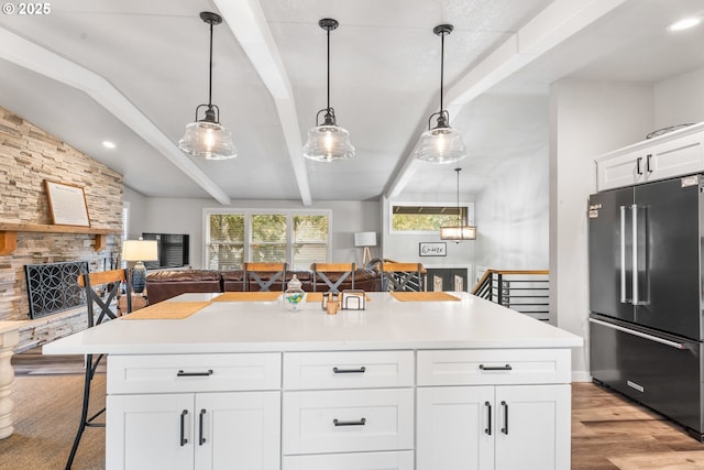 kitchen featuring high end fridge, a breakfast bar area, white cabinetry, a center island, and pendant lighting