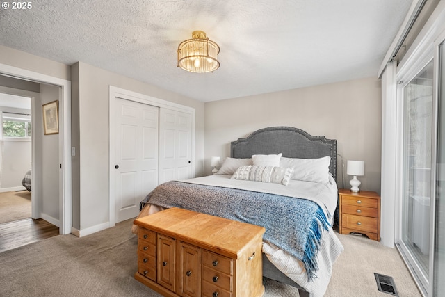 carpeted bedroom with a textured ceiling and a closet