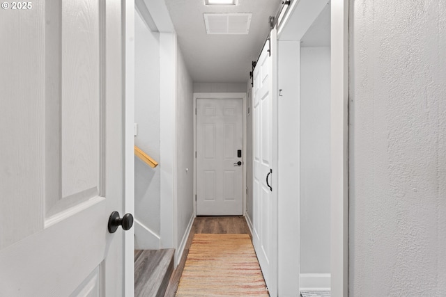 hallway with light hardwood / wood-style floors and a barn door