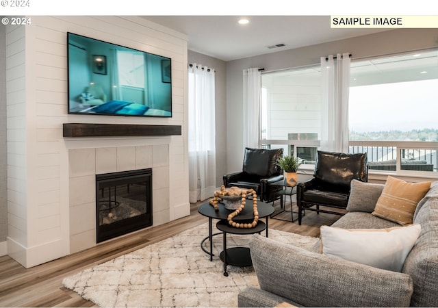 living room featuring wood-type flooring and a tiled fireplace