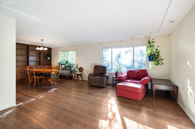 living room with built in features, dark wood-type flooring, and an inviting chandelier