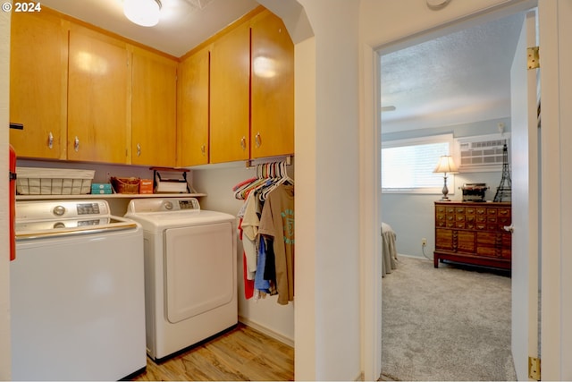 laundry area featuring washer and clothes dryer, light colored carpet, and cabinets