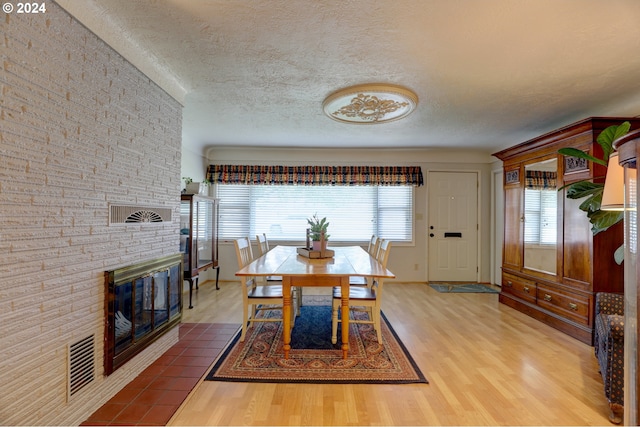 dining room featuring a fireplace, hardwood / wood-style floors, and a textured ceiling