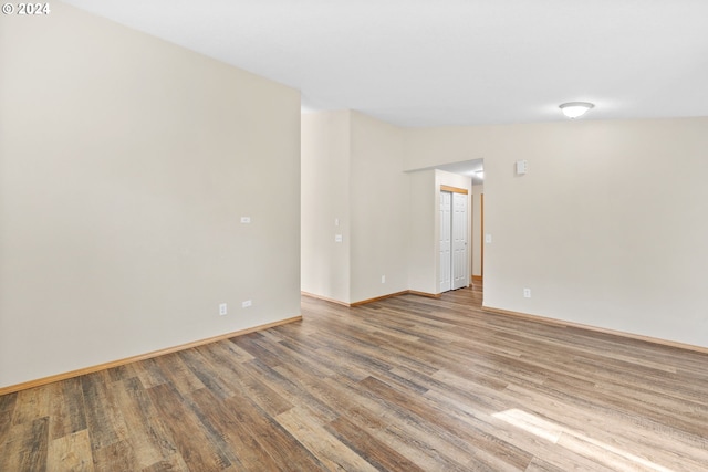 spare room featuring vaulted ceiling and wood-type flooring