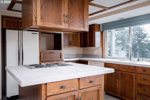 kitchen featuring tile countertops, a center island, white appliances, and sink