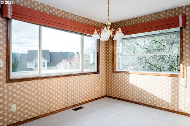 unfurnished room with a notable chandelier