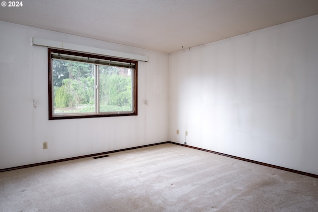 carpeted empty room with a textured ceiling