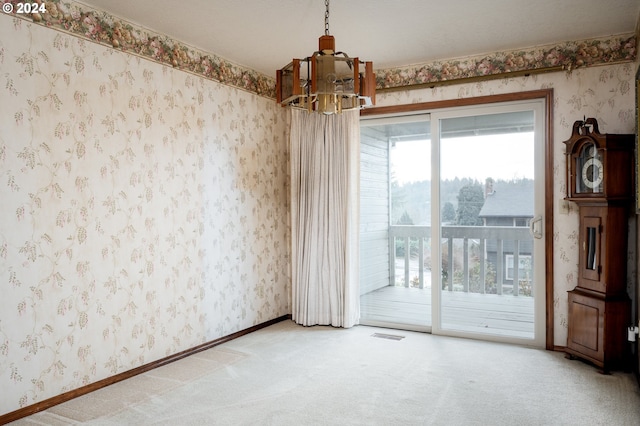 empty room featuring carpet flooring and an inviting chandelier