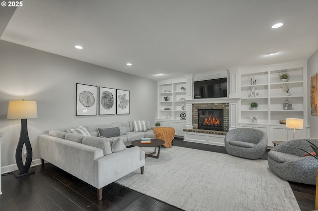 living room featuring built in shelves, dark hardwood / wood-style flooring, and a fireplace