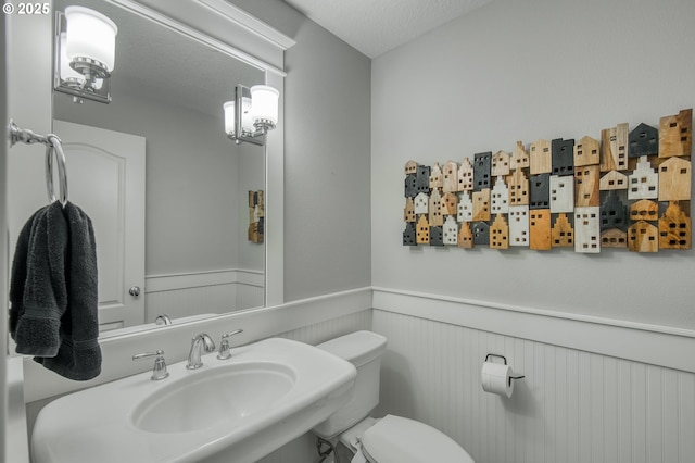 bathroom with a textured ceiling, toilet, and sink