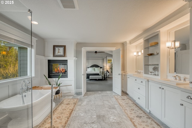 bathroom with a multi sided fireplace, a textured ceiling, vanity, and a tub to relax in