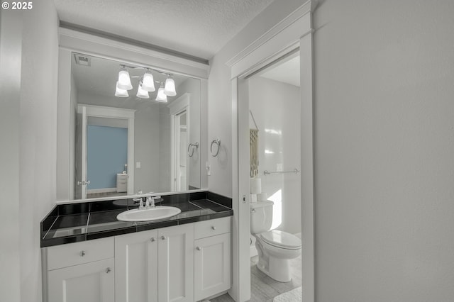 bathroom featuring vanity, a textured ceiling, and toilet