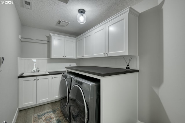 clothes washing area featuring cabinets, sink, dark hardwood / wood-style floors, separate washer and dryer, and a textured ceiling