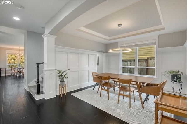 dining space with a tray ceiling, dark hardwood / wood-style floors, and a notable chandelier