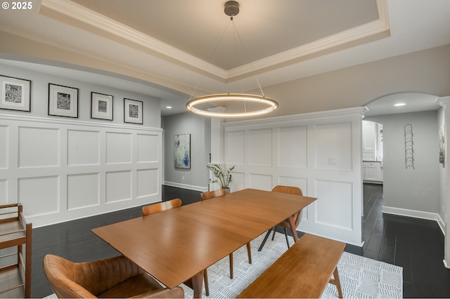 dining space with crown molding, a raised ceiling, and dark wood-type flooring